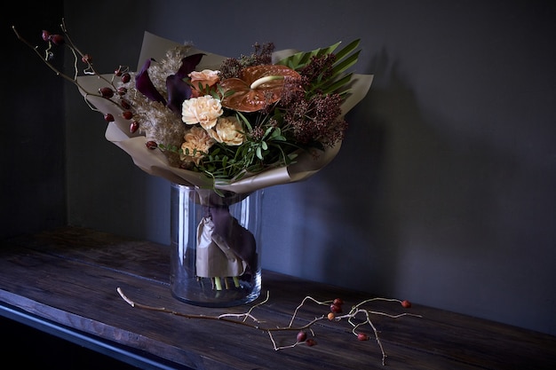 Nahaufnahmeblumenstrauß in einem Glasvase verziert in der Weinleseart auf einem dunklen Hintergrund