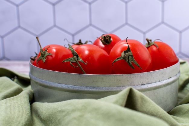 Nahaufnahmedetail einer Reihe Kirschtomaten in einem Metallbehälter mit grünem Tuch