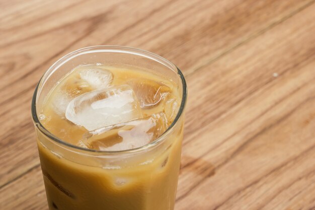 Nahaufnahmeeiskaffee im Glas auf Holztisch.