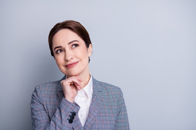 Nahaufnahmefoto der attraktiven Geschäftsdame gute Laune Lehrer schauen interessiert auf leeren Raum Hand am Kinn Planung zukünftigen Unterricht tragen karierten Blazer weißes Hemd isoliert grauer Farbhintergrund