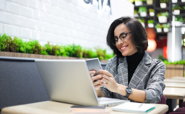 Nahaufnahmefoto der Geschäftsfrau im intelligenten Outfit, die Nachricht auf einem Smartphone schreibt und lächelt.