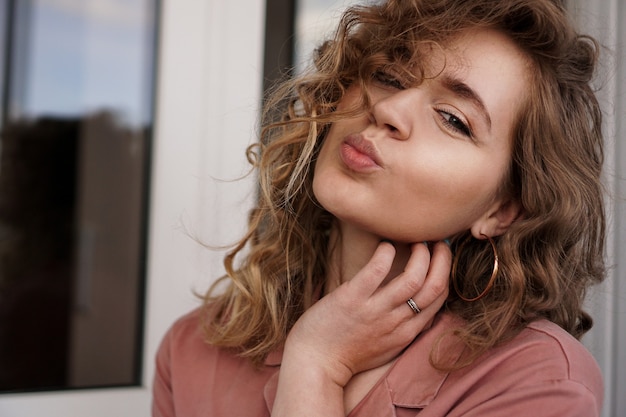 Nahaufnahmefoto der schönen lustigen hübschen lockigen Dame positive gute Laune, die Luftküsse sendet