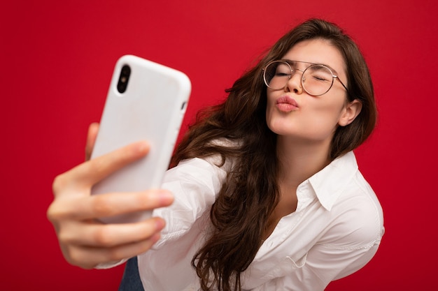 Nahaufnahmefoto der sexy schönen positiven jungen brünetten Frau, die weißes Hemd und optisches trägt