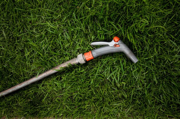 Nahaufnahmefoto des Gartenschlauchs, der auf frischem grünem Gras liegt