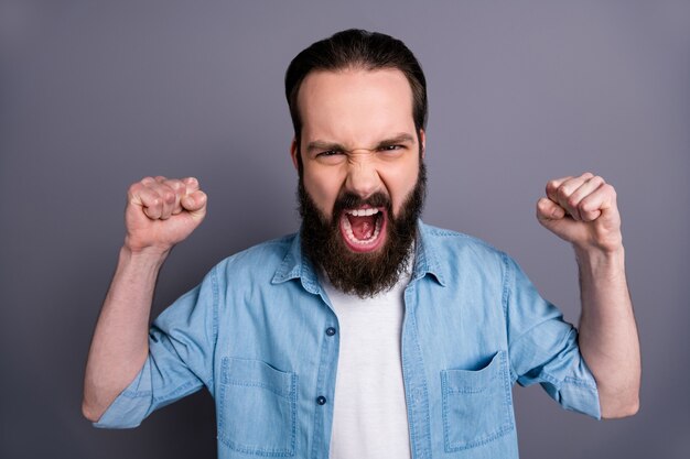 Nahaufnahmefoto des wütenden empörten Kerls haben Skandal Uneinigkeit mit seinem Freund, der Fäuste erhebt, schreien tragen stilvolle Kleidung, die über graue Farbwand isoliert wird