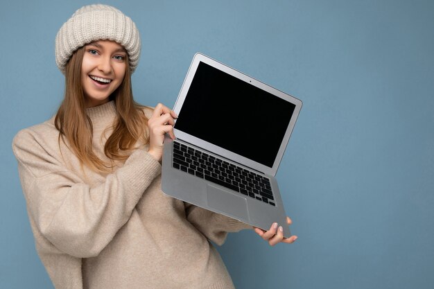 Nahaufnahmefoto-Porträt der schönen lächelnden jungen blonden Frau im warmen warmen beige Strickmütze des Winters