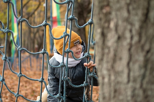 Nahaufnahmefotografie eines Jungen, der auf einer Strickleiter im Park klettert