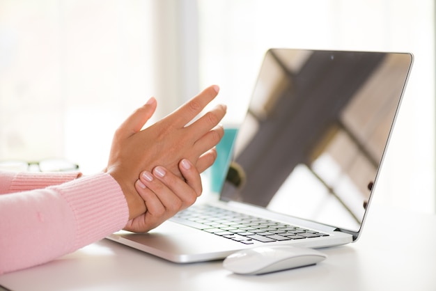 Nahaufnahmefrau, die ihre Handgelenkschmerz von der Anwendung des Computers hält. Büro-Syndrom.