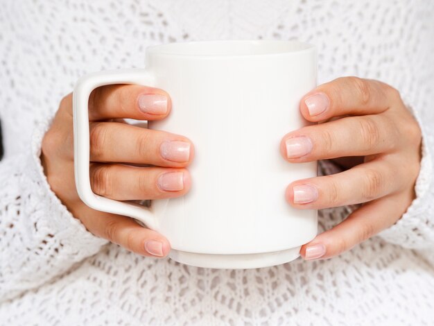 Nahaufnahmefrau mit Strickjacke und weißem Becher