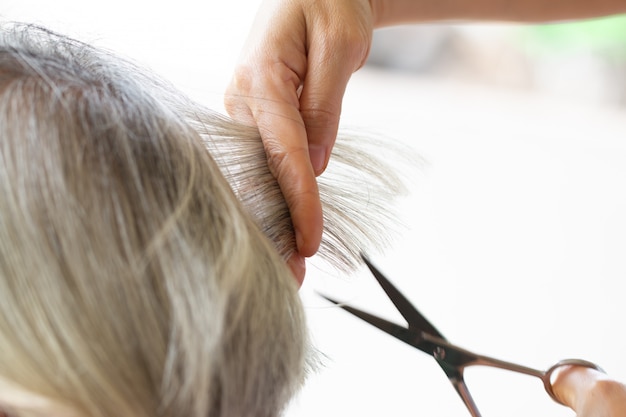 Nahaufnahmefriseur mit den Scheren, die Haar schneiden