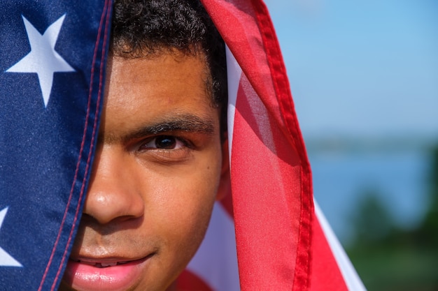 Nahaufnahmegesicht des glücklichen afroamerikanischen Mannes hüllt sich in die US-Flagge ein