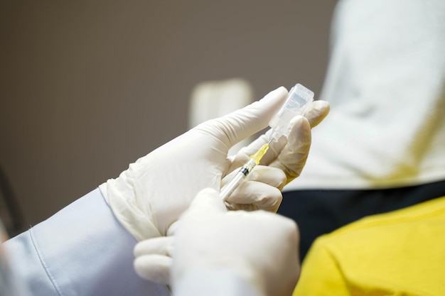 Foto nahaufnahmehände des arztes halten eine spritze in vorbereitung, um dem patienten eine injektion zu geben