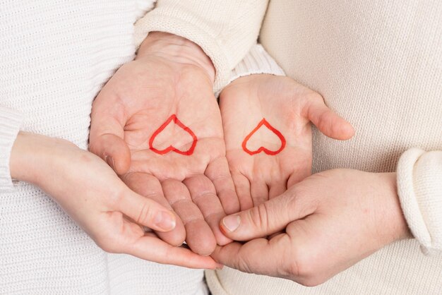 Nahaufnahmehände, die Herz auf rosafarbenem Hintergrund Valentinstagkonzept halten