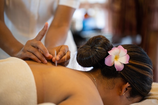 Nahaufnahmehände machen eine therapeutische Nackenmassage für ein Mädchen, das auf einer Massageliege in einem Massage-Spa liegt