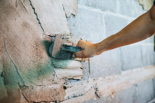 Nahaufnahmehand des Arbeiters, der Zement an der Wand für den Hausbau verputzt