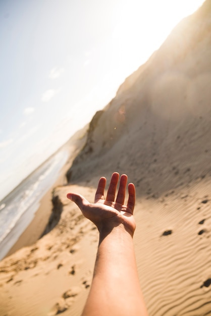 Foto nahaufnahmehand, die auf strandlandschaft zeigt