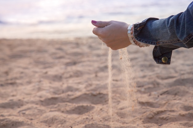 Nahaufnahmehand, die fallenden Sand freigibt. Sommer Strandurlaub Ferienkonzept