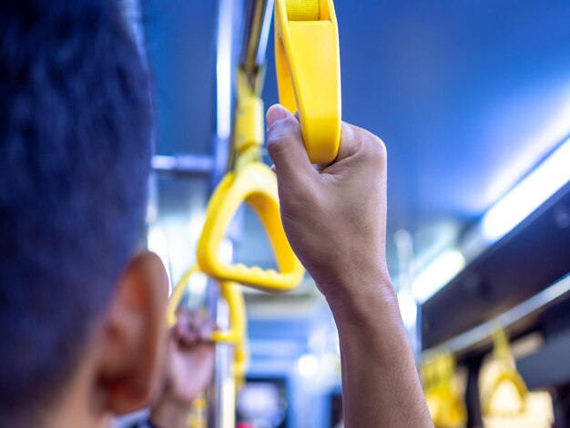 Nahaufnahmehand, die gelben Griff im Bus hält