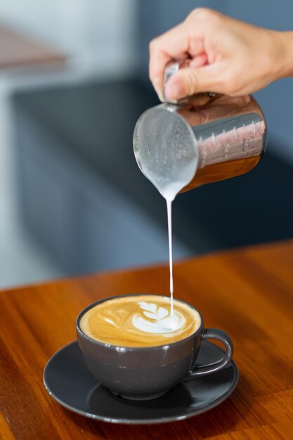 Nahaufnahmehand, die heißen Latte Art Kaffee tut