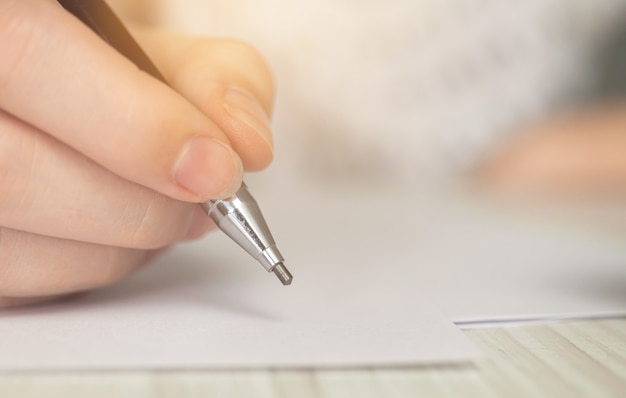 Nahaufnahmehandschrift, auf Holztisch. Konzept für Bildung, Lernen und Unterzeichnung von Dokumenten. Papierkram Hintergrundfoto