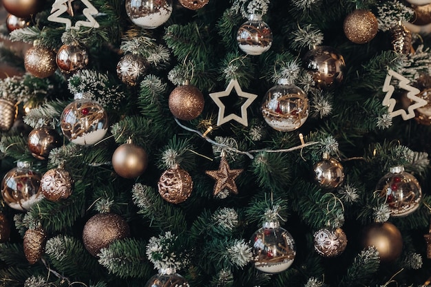 Nahaufnahmehintergrund des grünen flauschigen Weihnachtsbaums mit verschiedenen Dekorationen in Form von Engeln, Weihnachtskugeln, Sternen und Girlande.