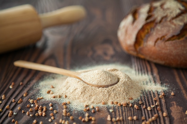 Nahaufnahmelöffel mit Buchweizenmehl auf einer Holzoberfläche. Alternatives Mehl. Glutenfreie und gesunde Ernährung.