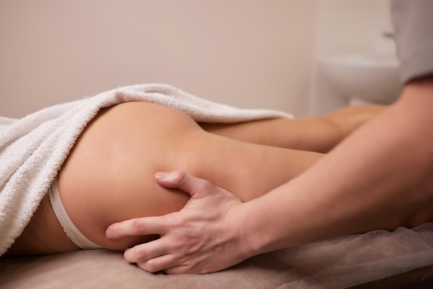 Nahaufnahmemasseur übergibt das Gießen von Massageöl auf den weiblichen Rücken und bereitet sich auf eine entspannende oder revitalisierende Massage vor.