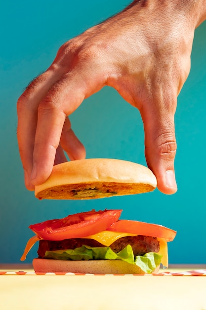 Foto nahaufnahmeperson mit burgerbrötchen und blauem hintergrund