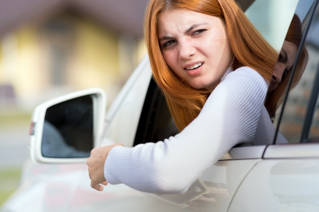 Nahaufnahmeporträt der angepissten verärgerten wütenden aggressiven Frau, die ein Auto fährt.