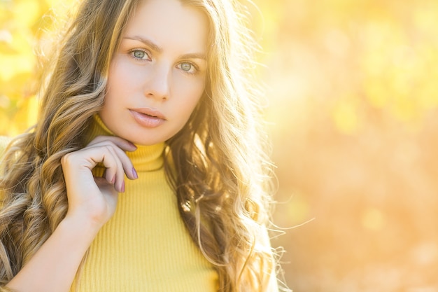 Nahaufnahmeporträt der attraktiven jungen Frau auf Fallhintergrund. Schöne blonde Frau auf Herbsthintergrund draußen.