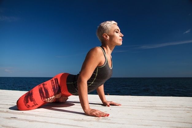 Nahaufnahmeporträt der erwachsenen blonden Frau mit kurzem Haarschnitt übt Yoga