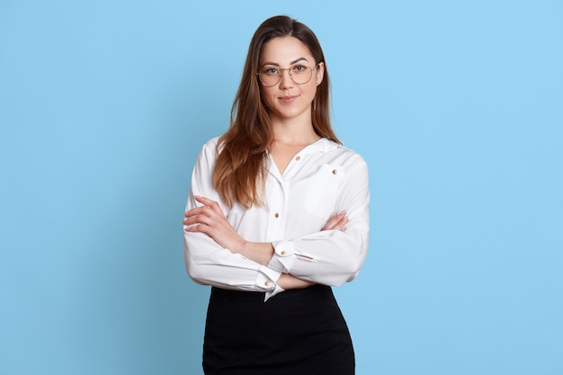 Nahaufnahmeporträt der Frau hält Brille mit Hand und schaut auf Kamera.