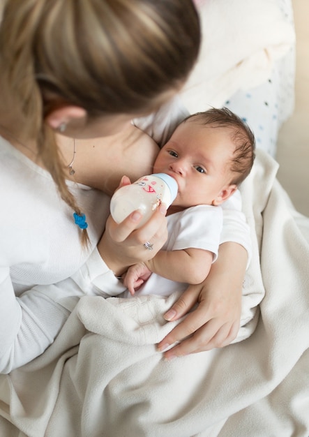 Nahaufnahmeporträt der jungen Mutter, die Baby mit Milch von der Flasche füttert