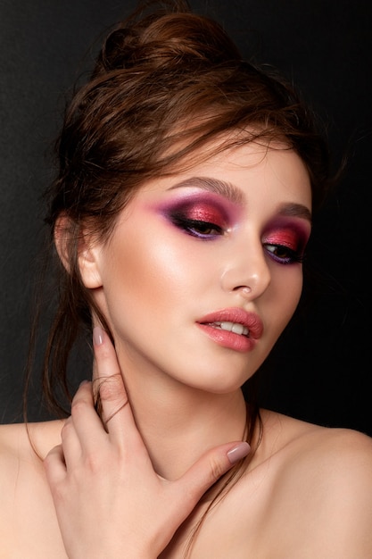 Nahaufnahmeporträt der jungen schönen Frau mit hellen rosa rauchigen Augen. Frau berührt ihren Hals. Mode Make-up. Modernes helles Sommer Make-up