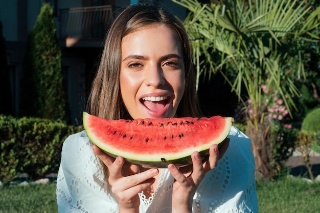 Nahaufnahmeporträt der jungen sinnlichen Frau, die Wassermelone isst Glückliche junge Frau mit Wassermelone im Park