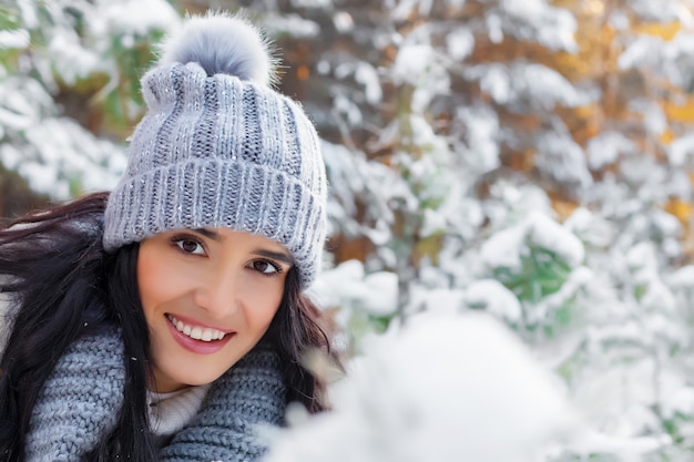 Nahaufnahmeporträt der lächelnden schönen jungen Frau im Wald im Winter