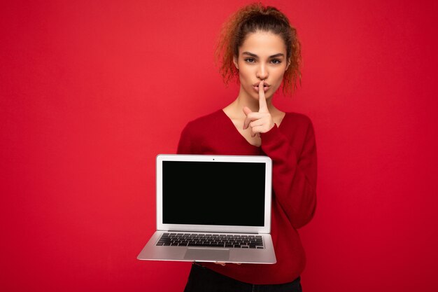 Nahaufnahmeporträt der schönen dunklen blonden lockigen jungen Frau, die Laptop-Computer hält