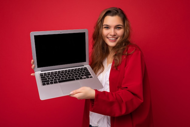 Nahaufnahmeporträt der schönen lächelnden glücklichen jungen Brunettefrau, die Computerlaptop mit leerem hält