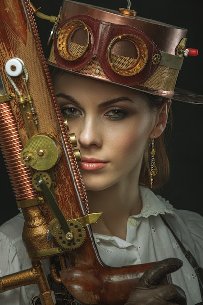 Nahaufnahmeporträt der Steampunk-Frau mit einer Waffe in seiner Hand.