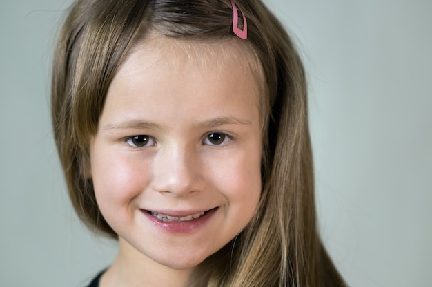 Nahaufnahmeporträt des glücklichen lächelnden kleinen Mädchens mit langen Haaren.