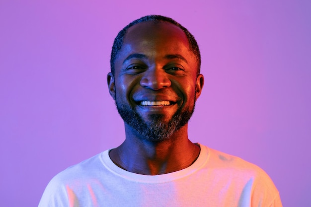 Nahaufnahmeporträt des hübschen schwarzen Mannes auf Neonhintergrund