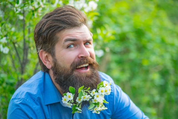 Nahaufnahmeporträt des lustigen Mannmodells mit Schnurrbärten und Bart mit Flovers im Hemdblütenbart