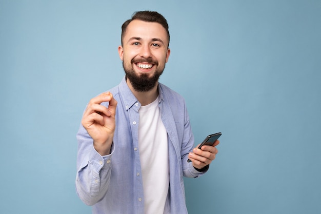 Nahaufnahmeporträt des positiven emotionalen gut aussehenden jungen Brunet-bärtigen Mannes, der lässiges Blau trägt