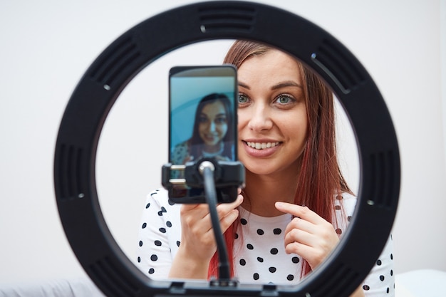 Nahaufnahmeporträt des schönen frauen-blogger-live-streams mit einem modernen smartphone, ringlampe.