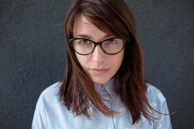 Nahaufnahmeporträt einer jungen attraktiven Frau mit Brille auf dunklem Hintergrund