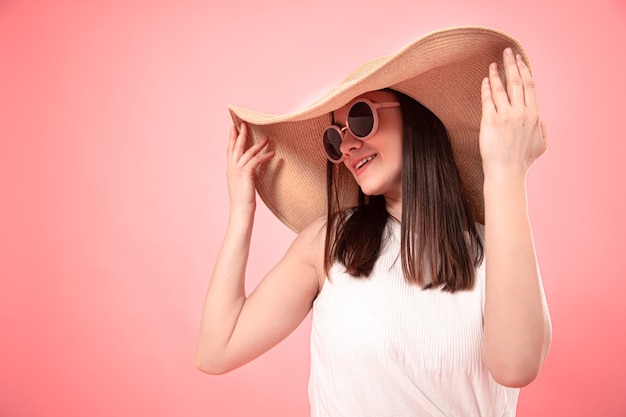 Nahaufnahmeporträt einer jungen Frau in einem großen Sommerhut und in der Sonnenbrille. Das Konzept des Sommers.