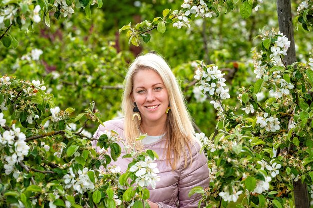 Nahaufnahmeporträt einer lächelnden blonden Frau in einem blühenden Garten im Frühjahr selektiver Fokus