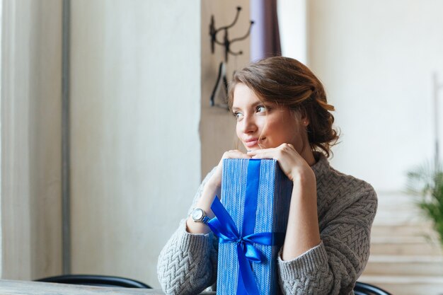 Nahaufnahmeporträt einer lächelnden Frau mit der Geschenkbox, die Kamera betrachtet