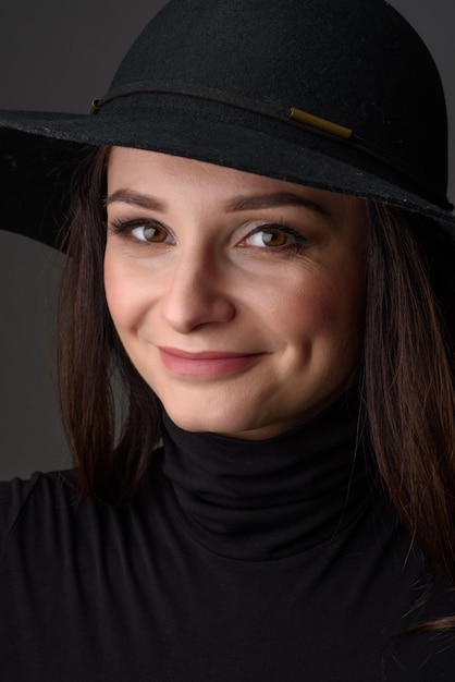 Nahaufnahmeporträt einer schönen Frau, die einen schwarzen Hut trägt.