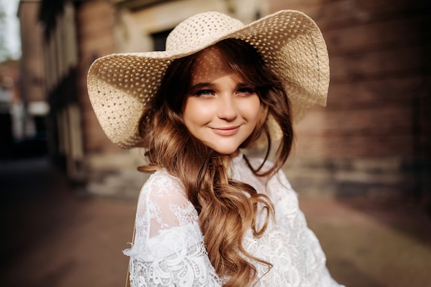 Nahaufnahmeporträt einer schönen Frau in einem Vintagen Sommerhut. Eine schöne Frau in einem Boho-Strohhut und Kleid.